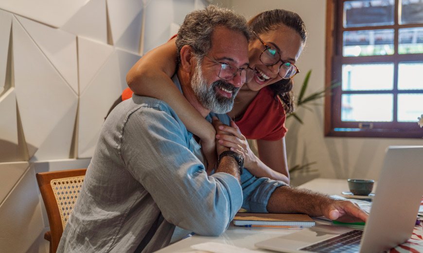 Dos personas sonriendo mirando una pantalla de computador